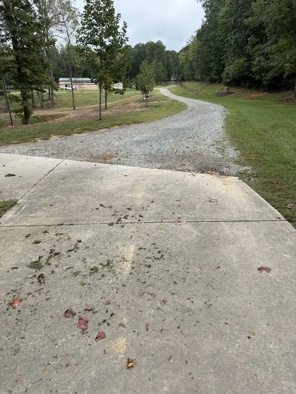 Rutted gravel and dirt driveway before replacement, wooded lot