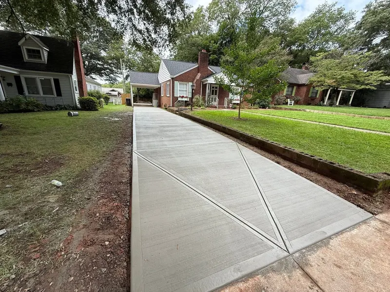 New concrete driveway with diagonal control joints running to a brick home
