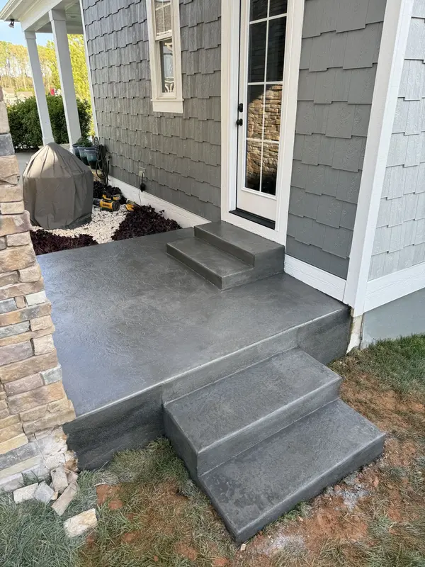 Charcoal stamped concrete landing and steps against gray shake siding