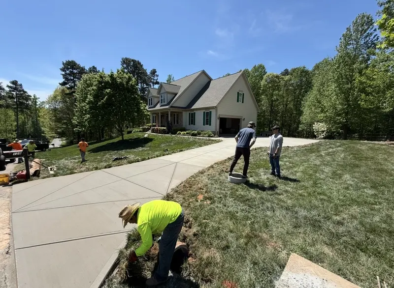 Finished wide concrete driveway and turnaround with the crew completing edge work